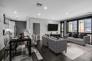 A modern living room with a dining table and grey sofa.